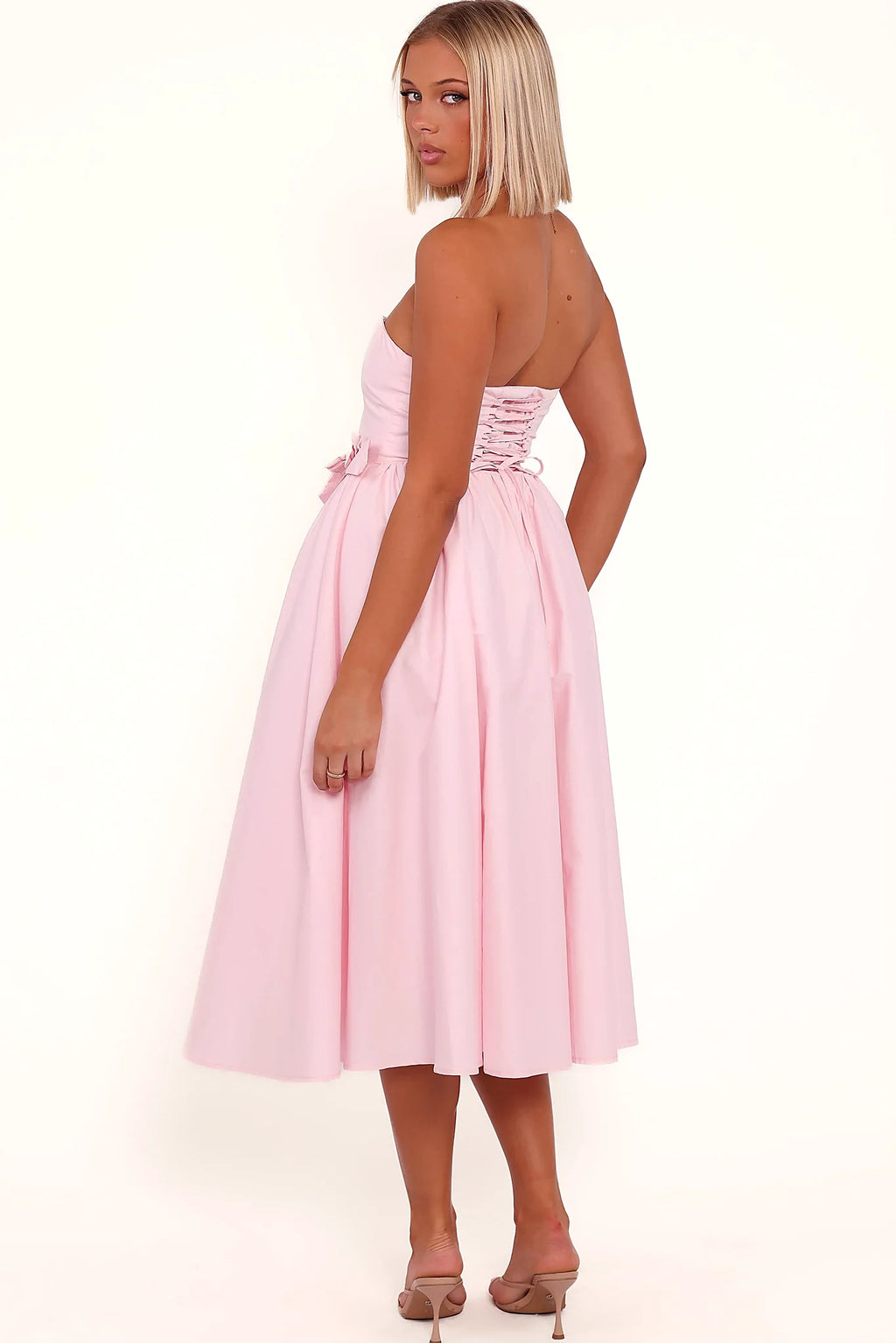 Full length view of a pink strapless occasion midi dress